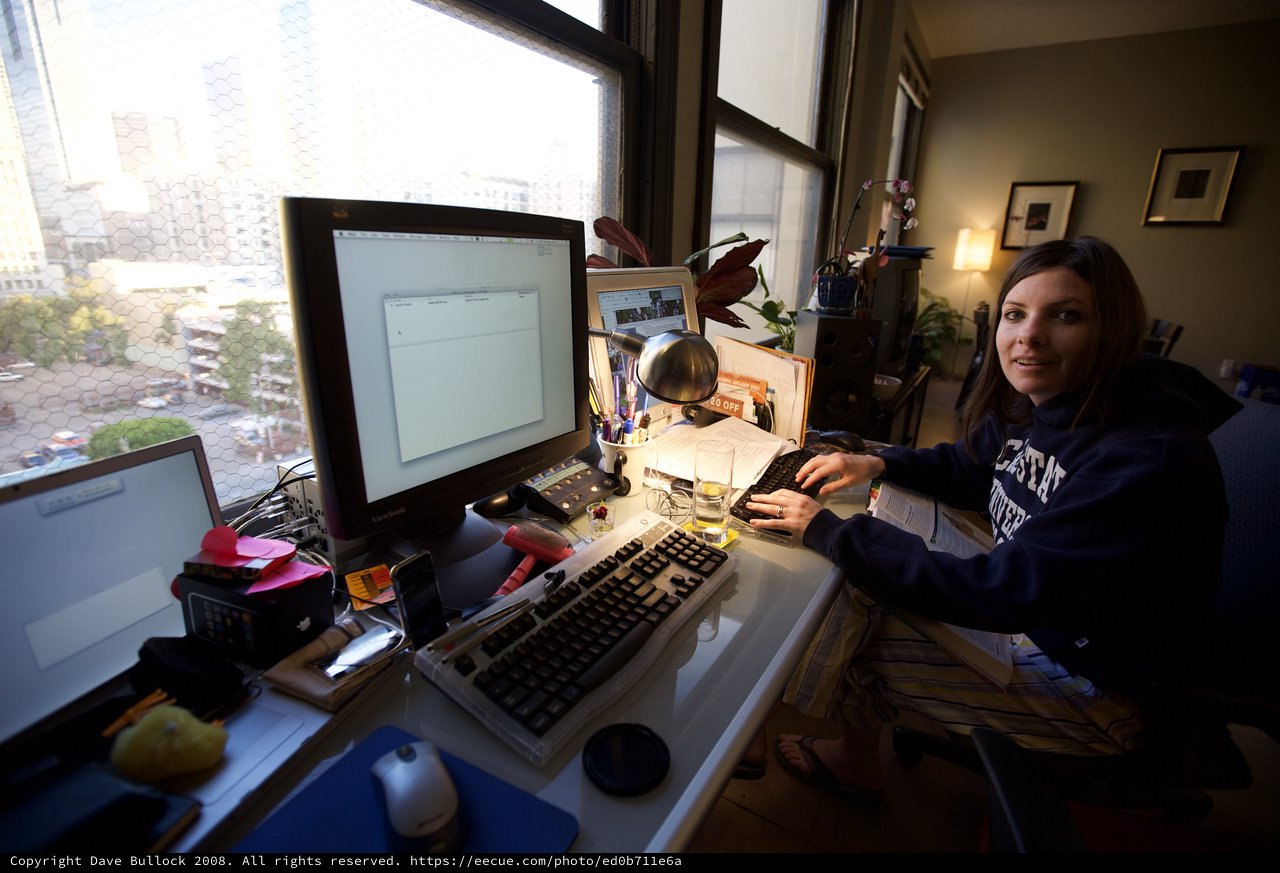 Young Woman Working at Cluttered Multi-Monitor Desk Setup