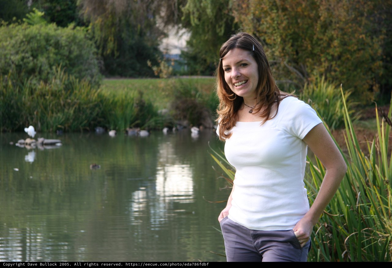 Smiling Woman Posing by Tranquil Park Pond