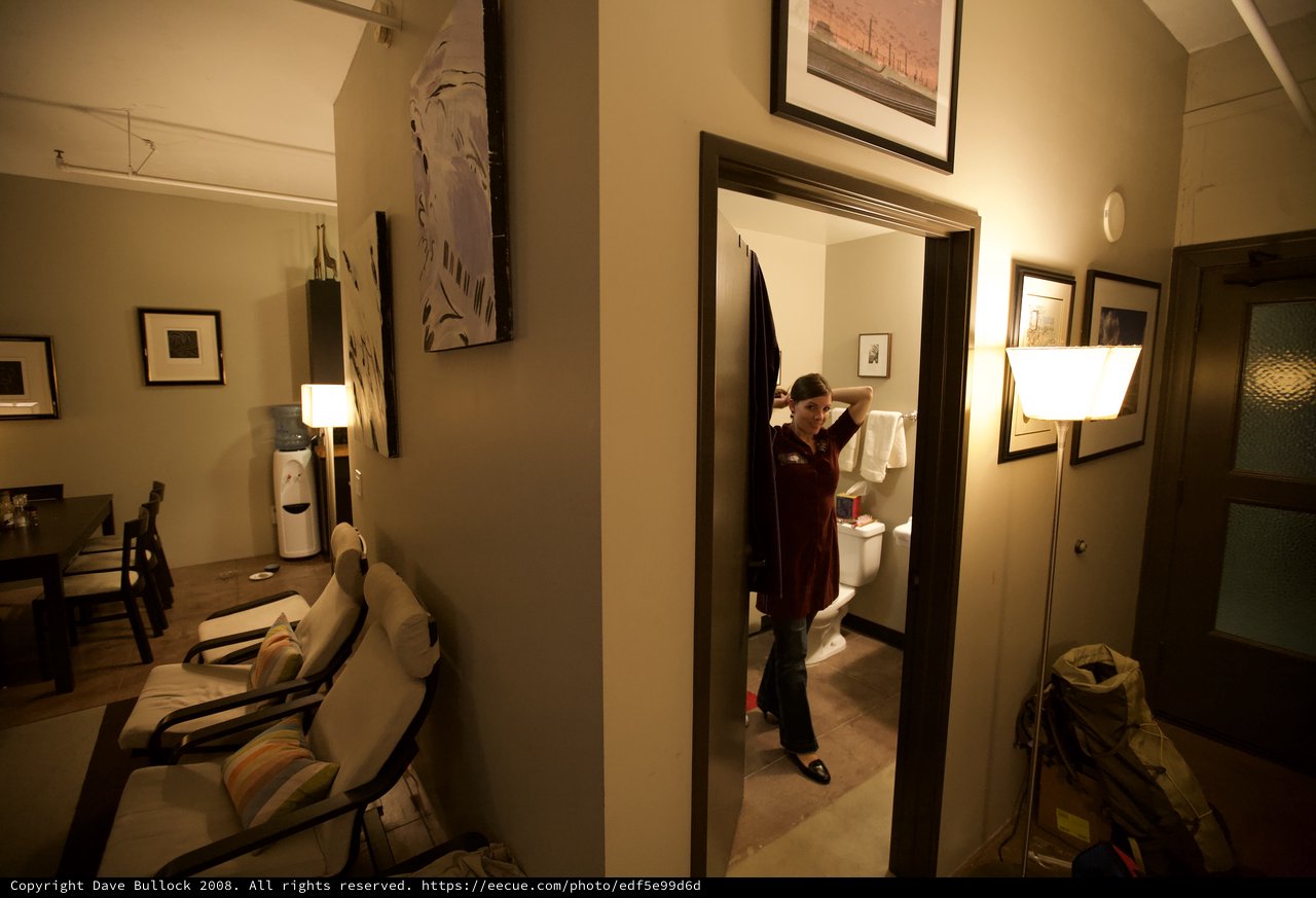 Woman Fixing Hair in Warmly Lit Home Bathroom