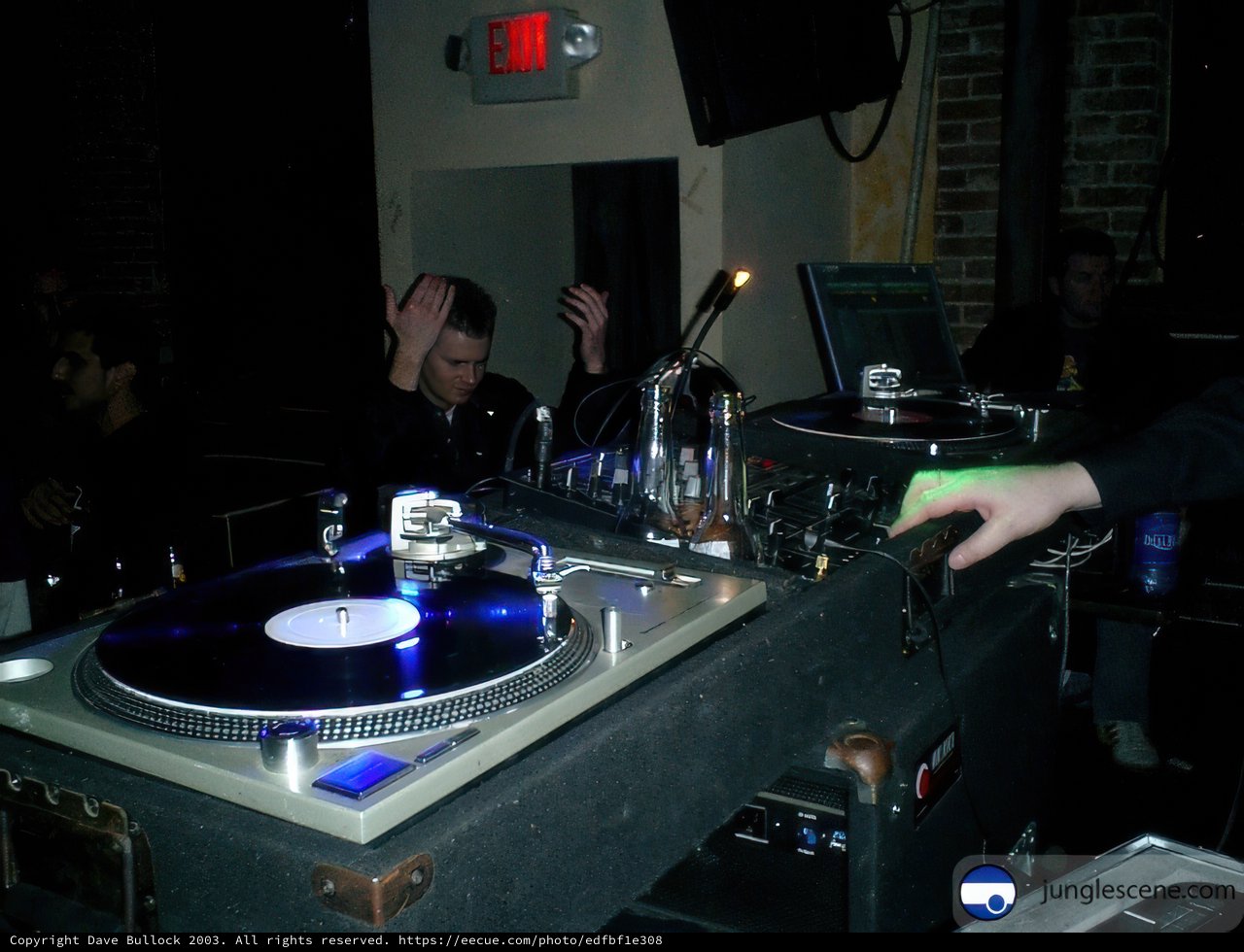 Spinning the Beats Caption: A DJ entertains the crowd with his turntable and speaker set up at a lively music event.