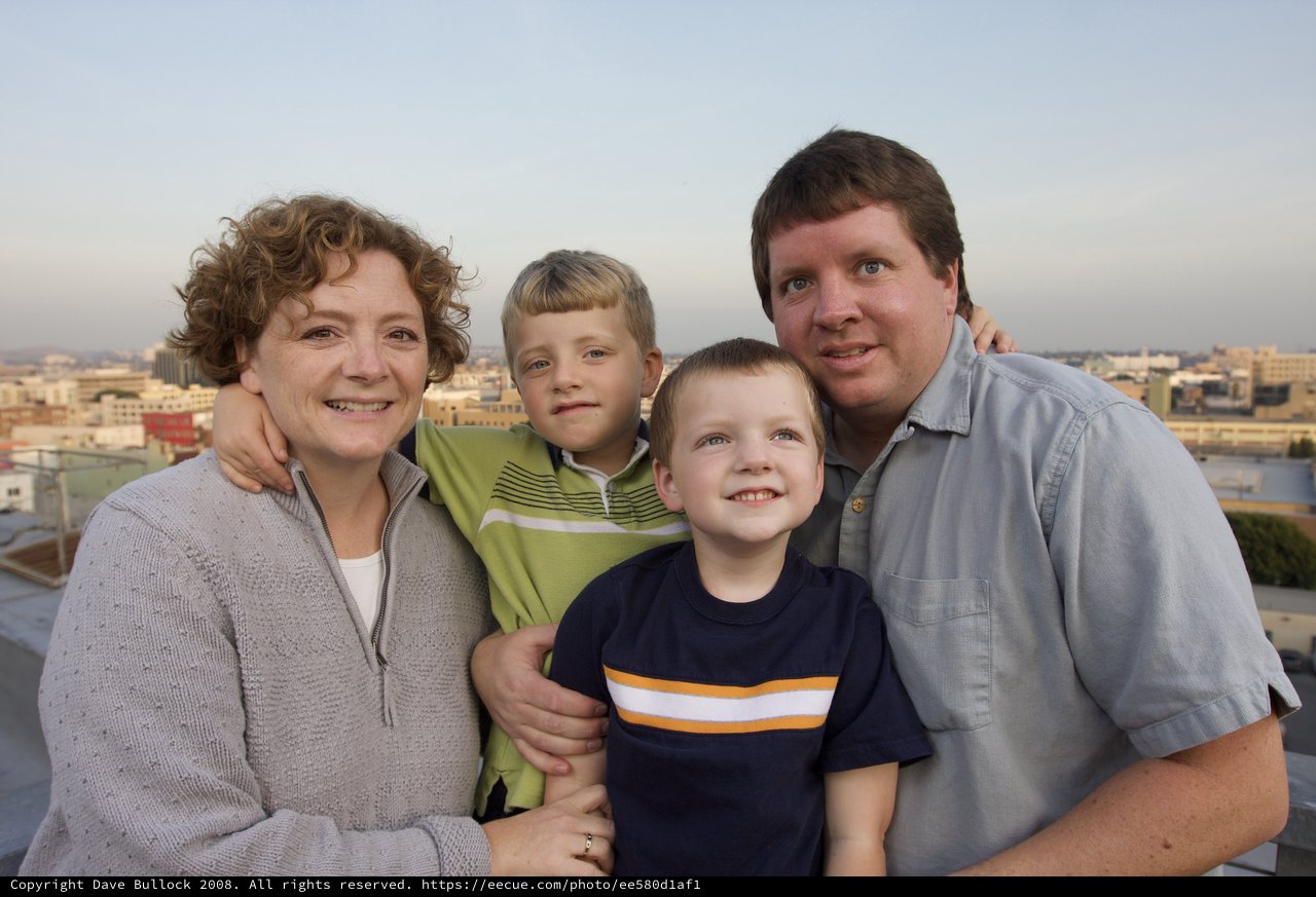 Family of Four Smiling on Urban Rooftop at Dusk