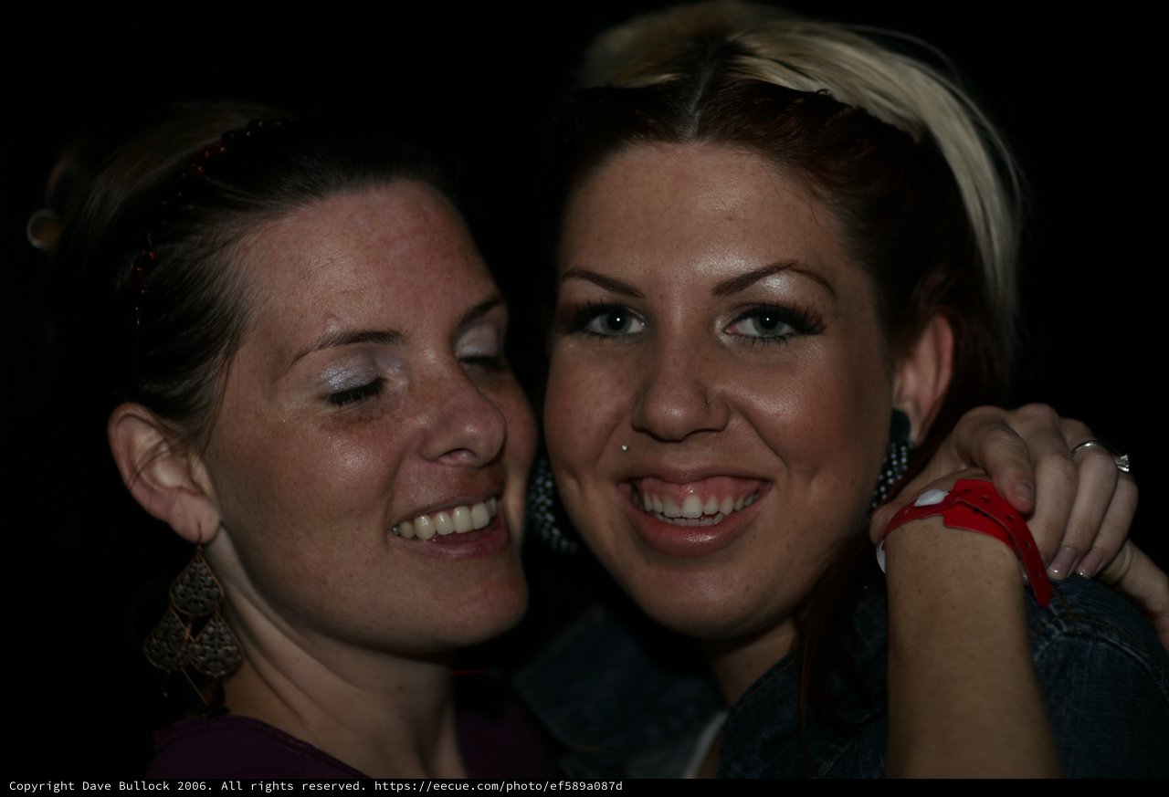 Two Friends Smiling Together at Nighttime Event