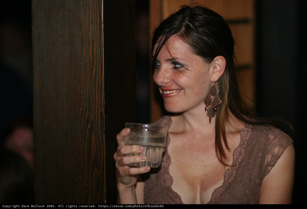 Woman Smiling with Drink at Evening Social Event