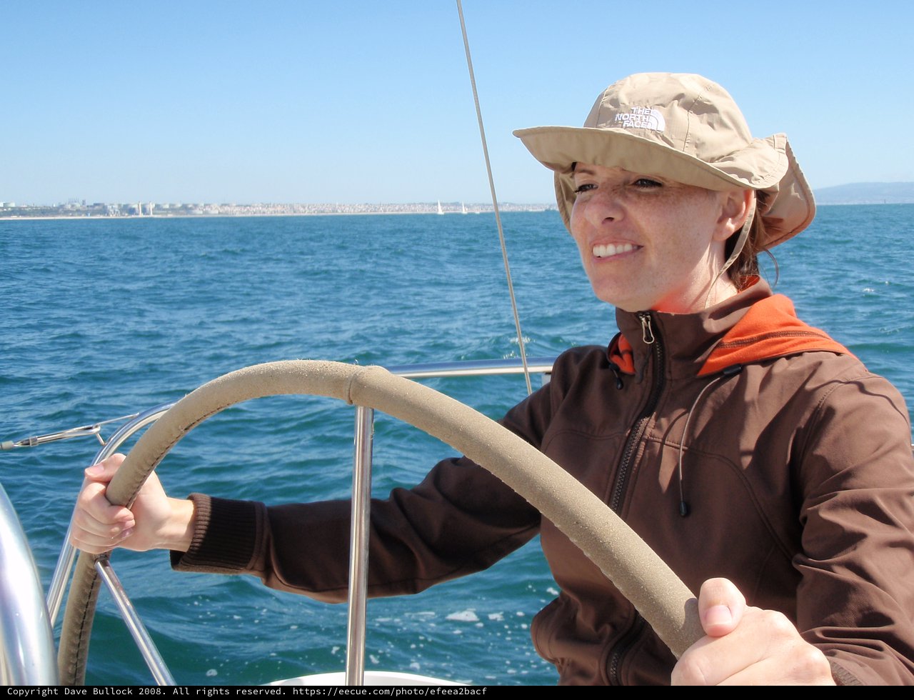 Woman Confidently Steering Sailboat on Open Water