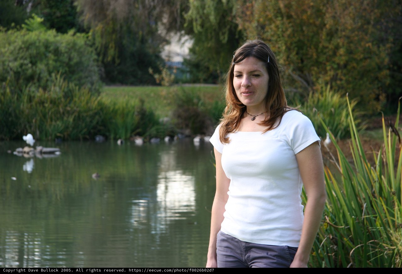 Young Woman by Tranquil Park Pond at Dusk