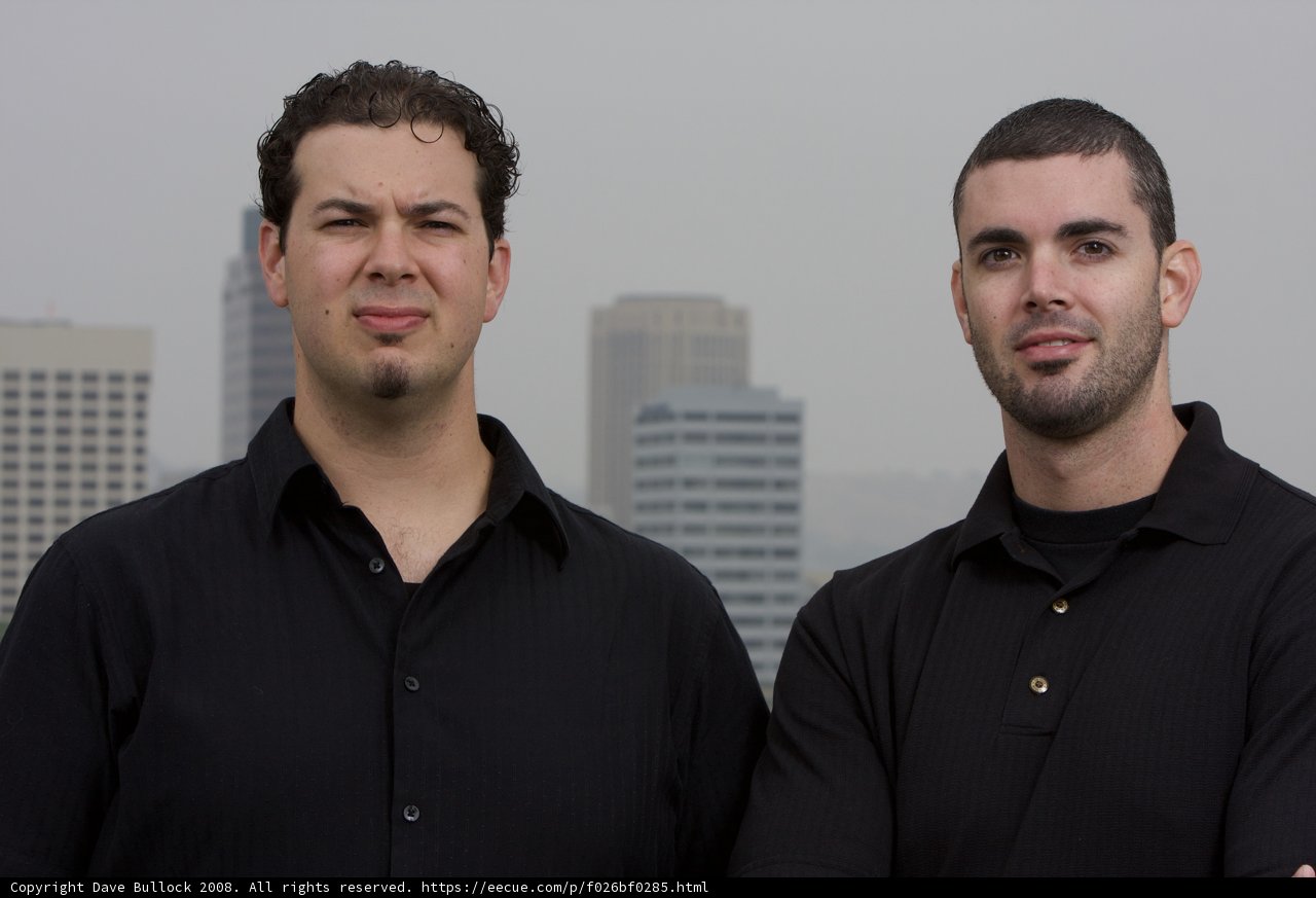 Two Happy Men Pose in Front of Skyscraper
