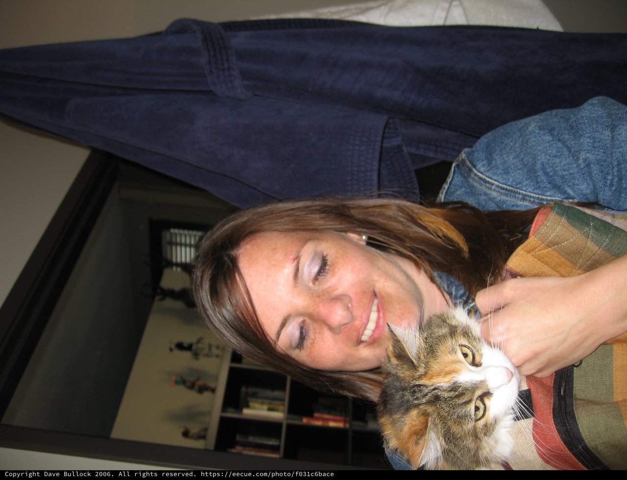 Woman Smiling Warmly While Cuddling Calico Cat