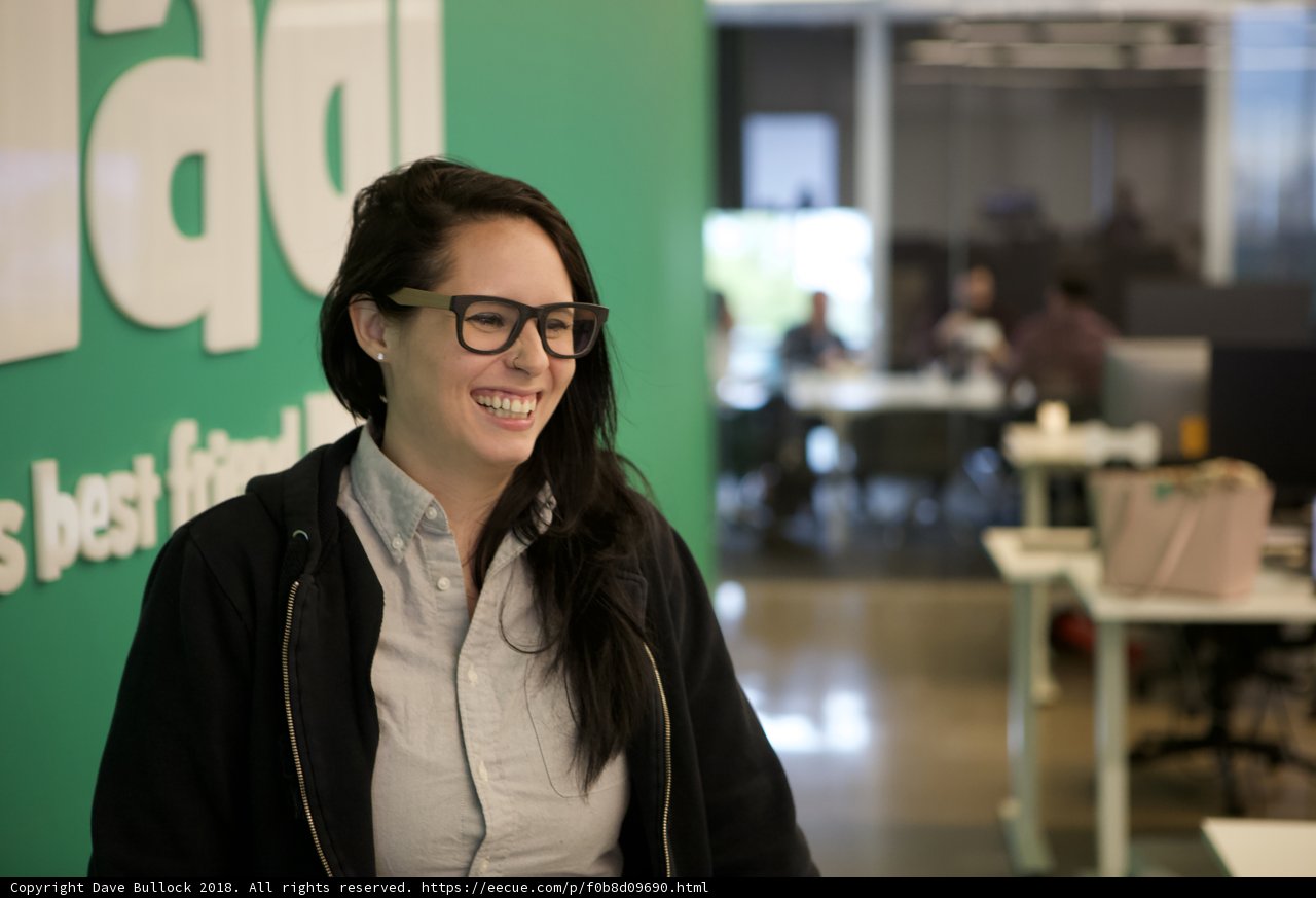 Woman in Glasses Smiling in front of Green Wall