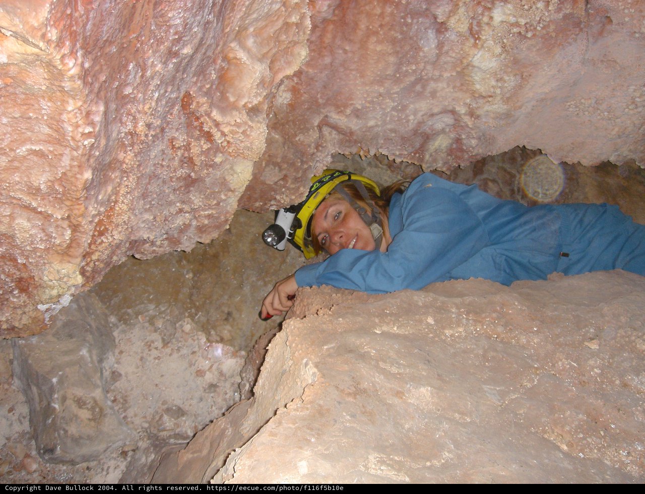 Caver Squeezing Through Tight Underground Rock Passage
