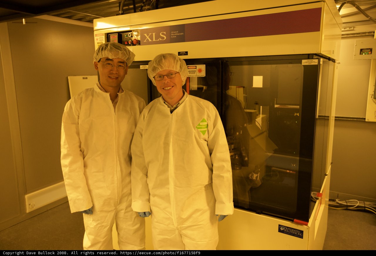 Two Men in White Suits Operating High-Tech Equipment