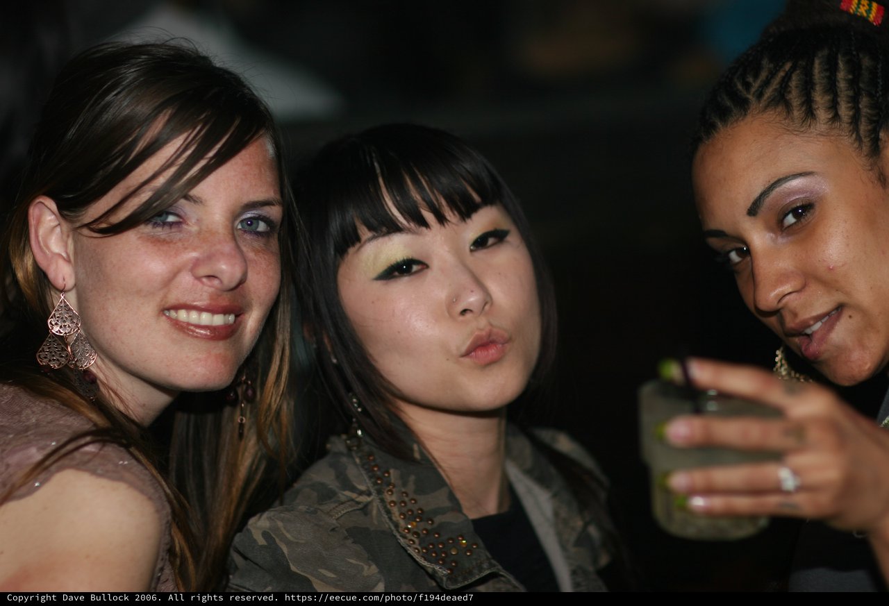 Three Friends Posing Together at a Nightclub Event