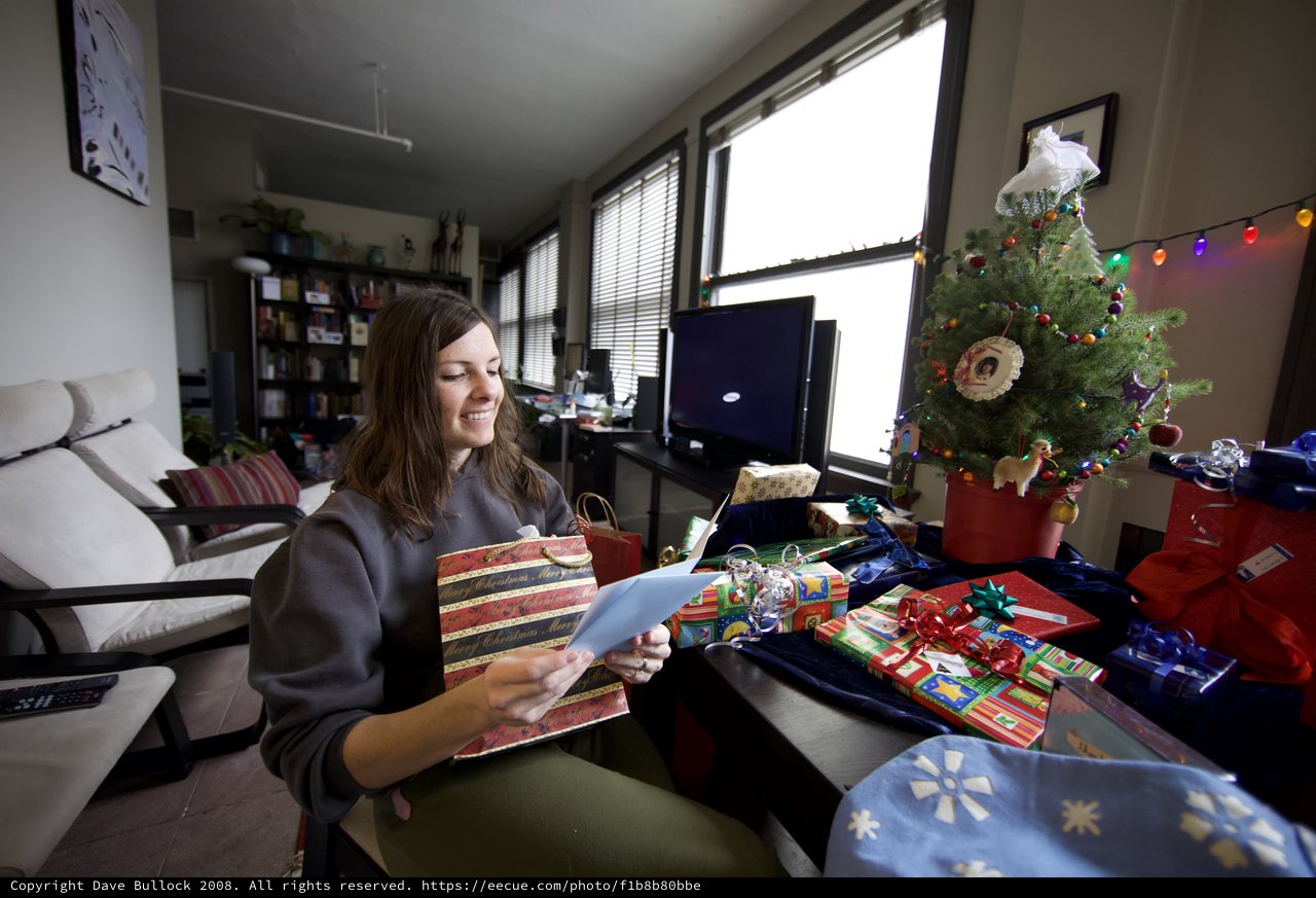 Woman Smiling While Reading Christmas Card at Home