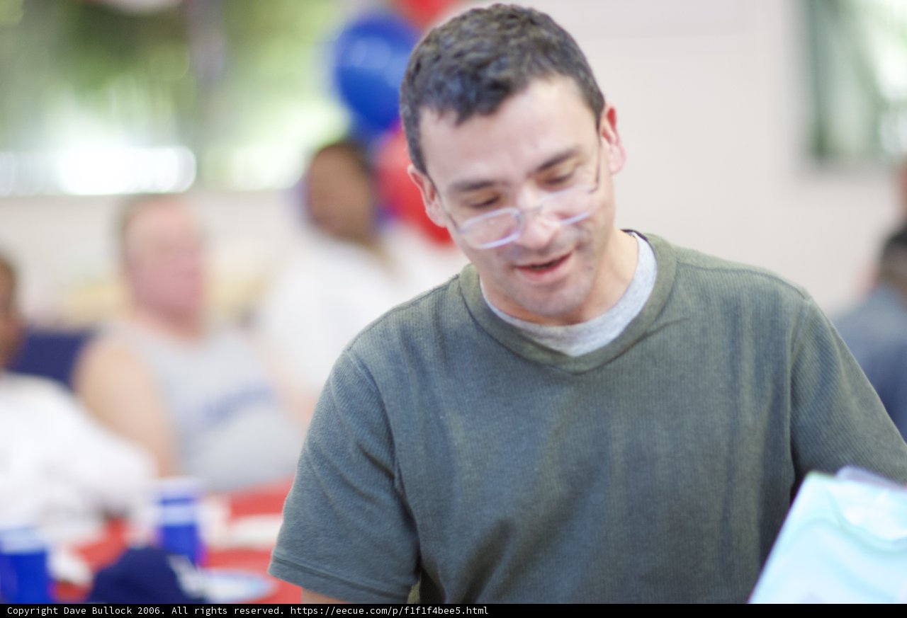 Smiling man with glasses holding paper