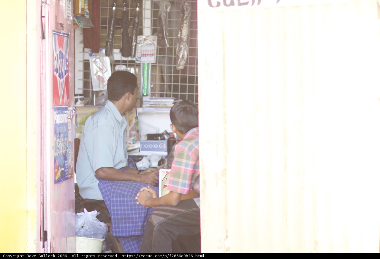 Man Sitting and Waiting at Newsstand