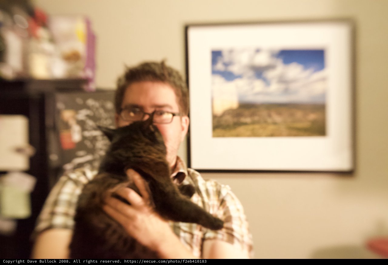 Man Holds Dark Cat Up to His Face
