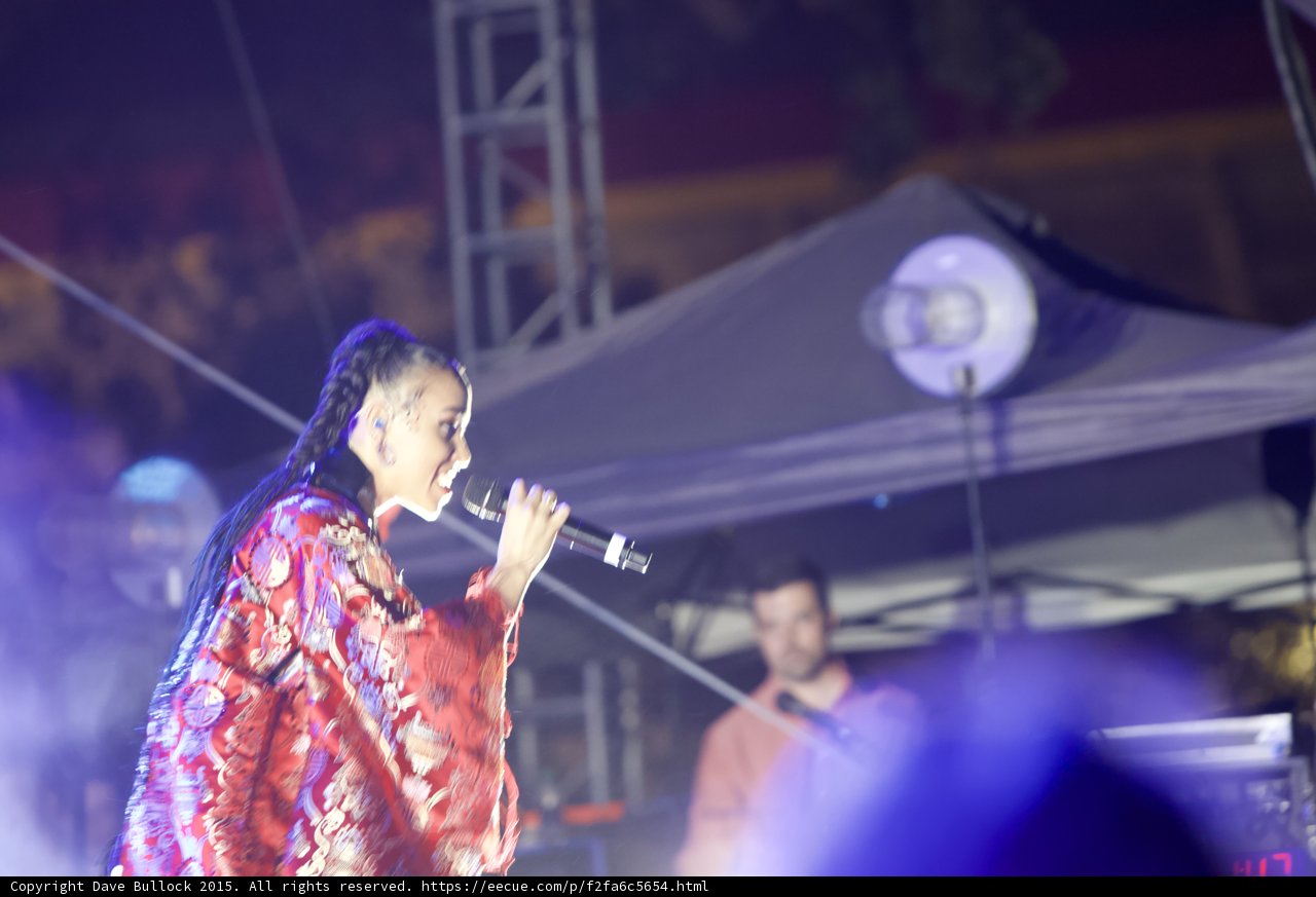 FKA twigs Upper Body Profile Singing Baby Hairs Swirls Earrings Braided Ponytail Kimono Red Brocade Gold Purple Patterns Stage Truss Canopy Band Drums Haze