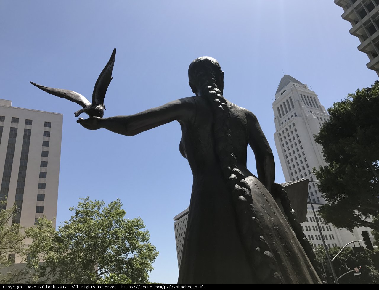 Woman and Bird Statue against the Urban Skyline