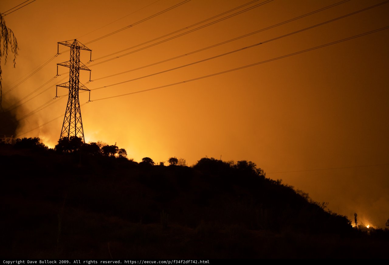 Blaze Engulfs Electric Transmission Tower and Surrounding Buildings