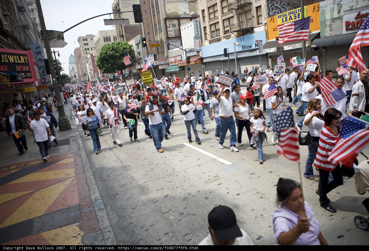 The Great American Boycott Parade Caption: A group of diverse individuals proudly walk down the street holding American flags during the Great American Boycott protest in 2007.