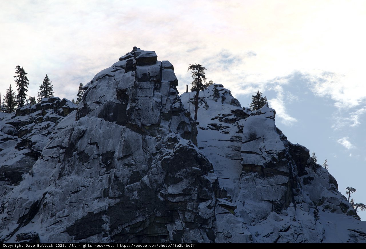 Lone Climber Reaches Summit of Snow-Covered Rocky Peak