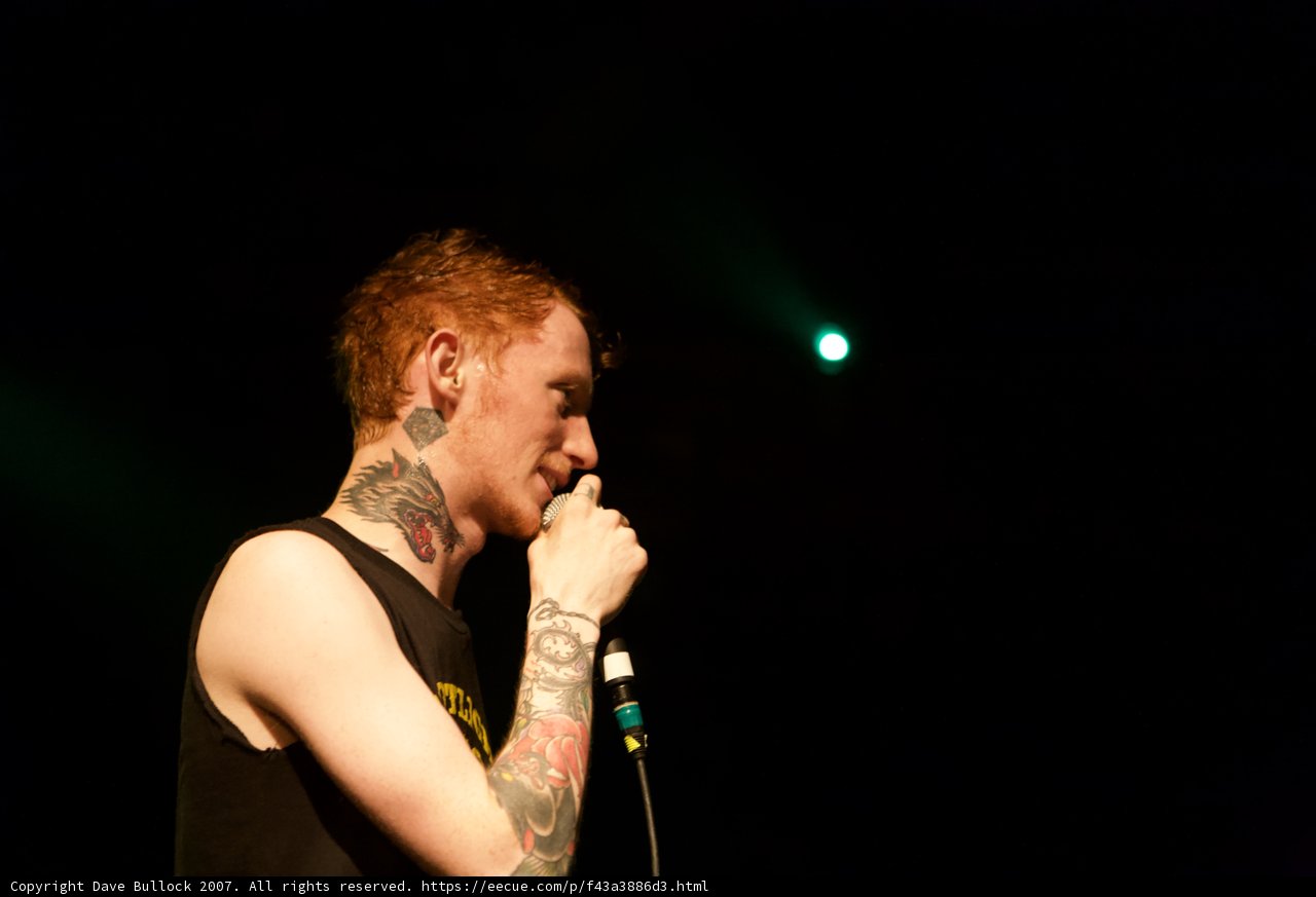 Tattooed man singing passionately with a microphone