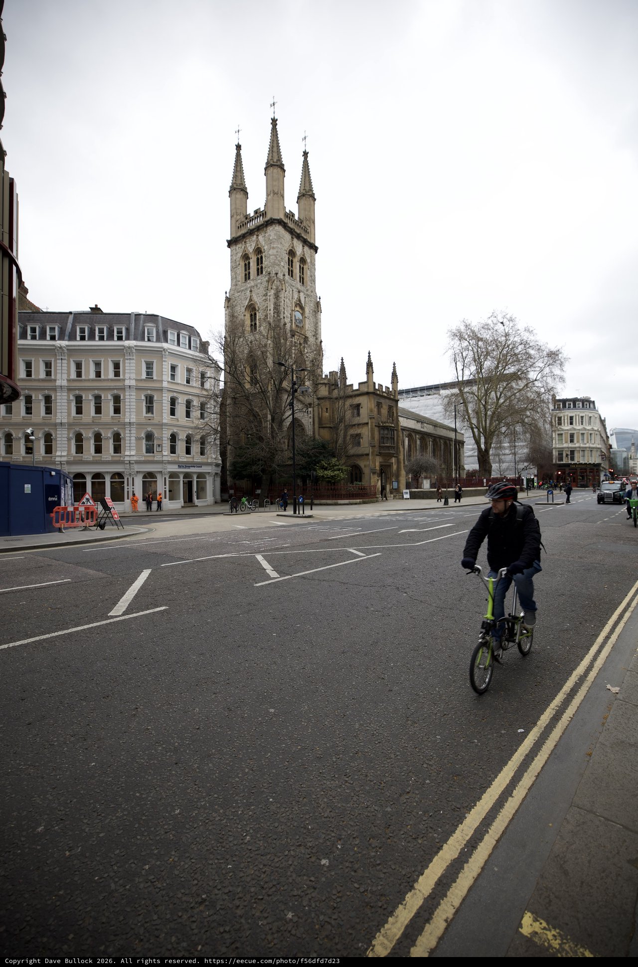 Cyclist Passes Historic Church on Overcast London Morning
