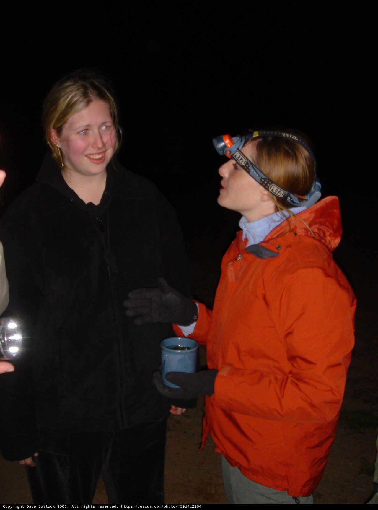 Night Campers Share Warm Drinks in Darkness