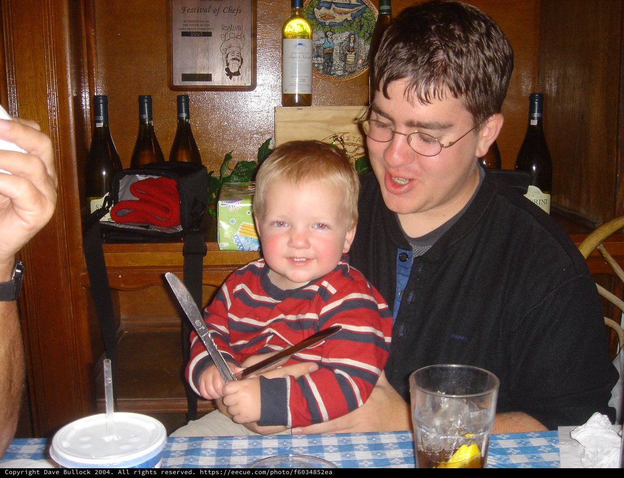 Toddler Grins Mischievously Holding Knife at Restaurant