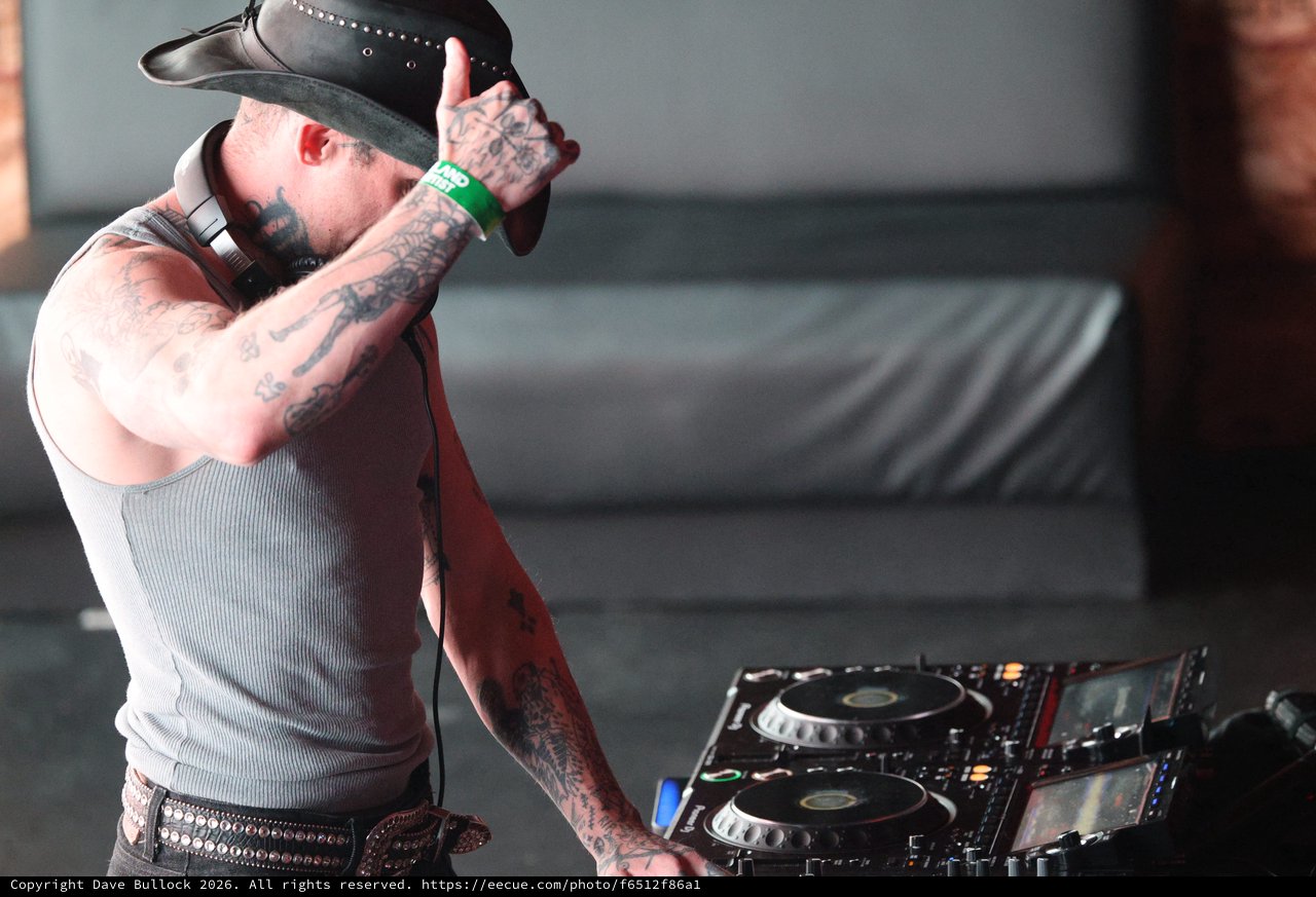 Tattooed DJ in Cowboy Hat Works the Decks