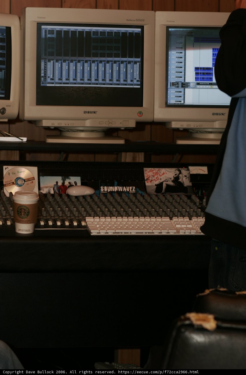 Blue-shirted man working on a computer in a tech-filled room