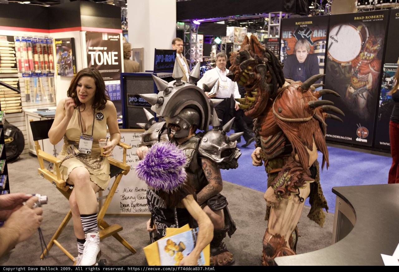 Cosplay Lovers Caption: Ray Luzier poses with two women dressed as characters at the 2009 NAMM convention. The exhibit hall is filled with art, clothing, and accessories for all tastes.
