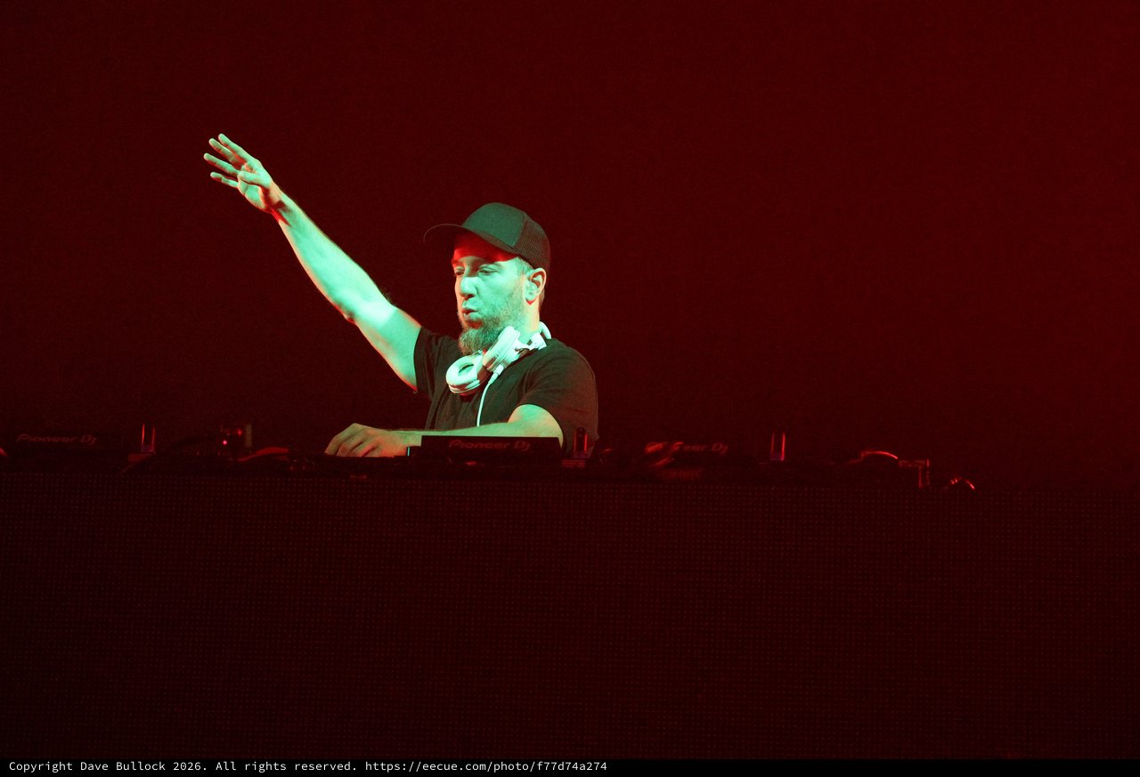 DJ Raises Hand Under Dramatic Red Stage Lights