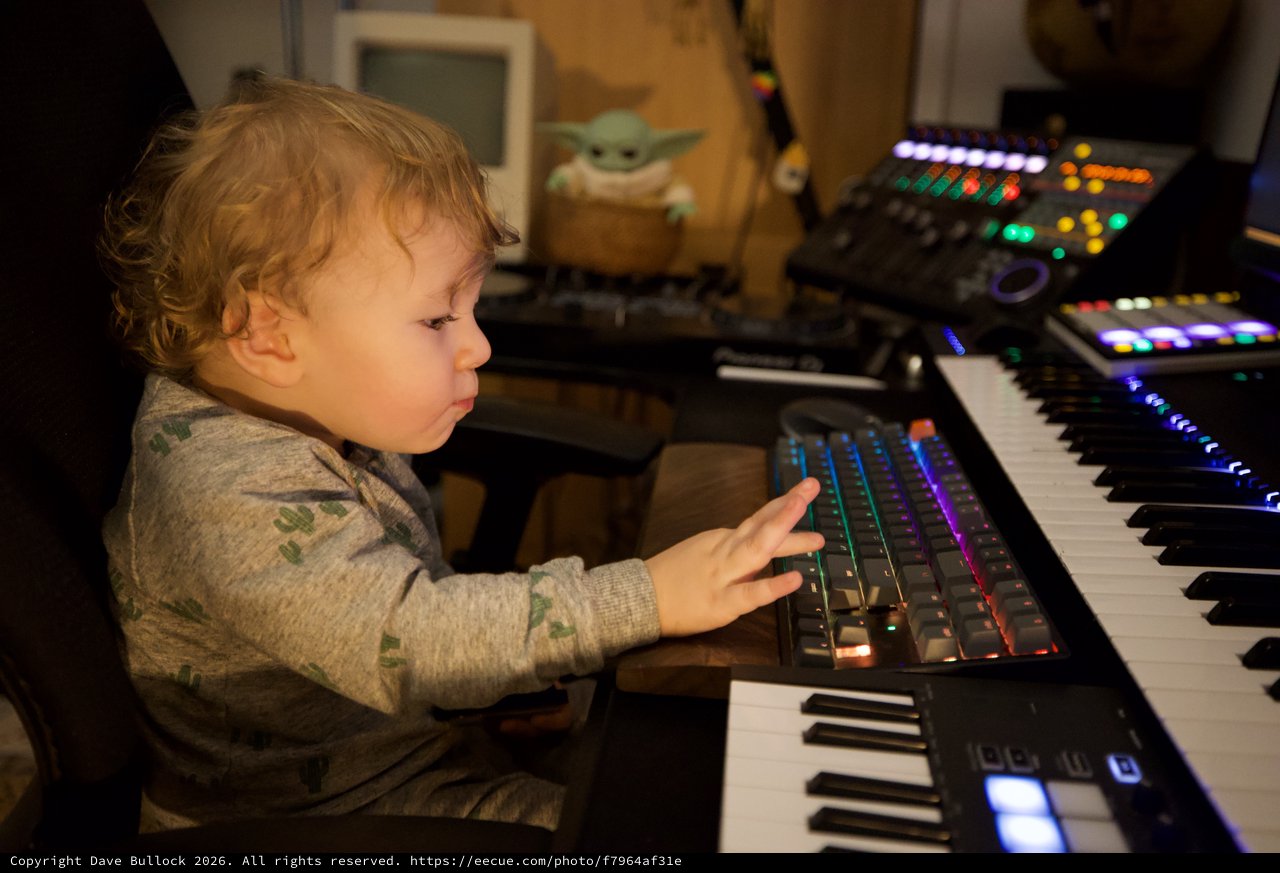 Young Child Exploring Music Production Equipment at Night