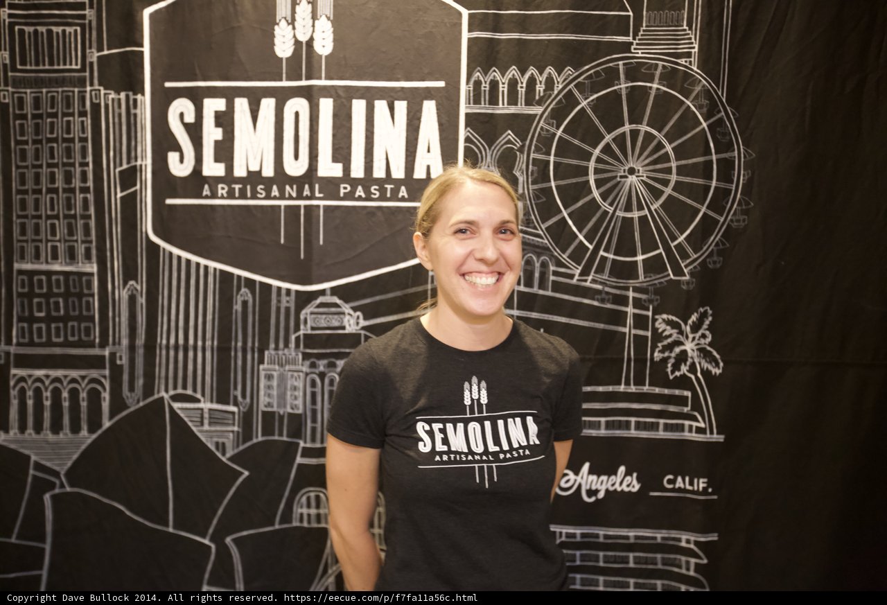 A Happy Woman Stands in Front of a Semolina Sign