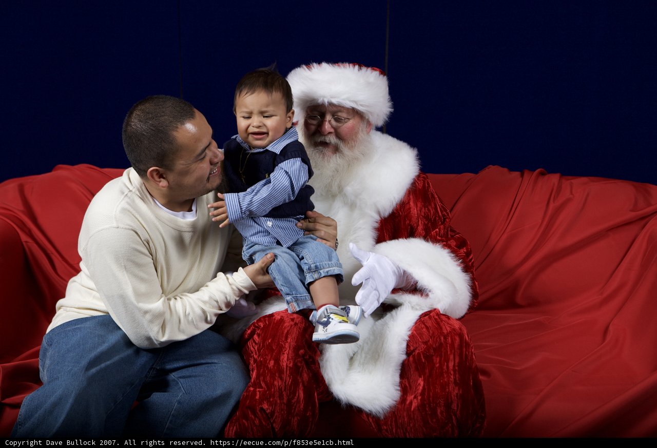 Santa Claus and a Little Helper on the Red Couch