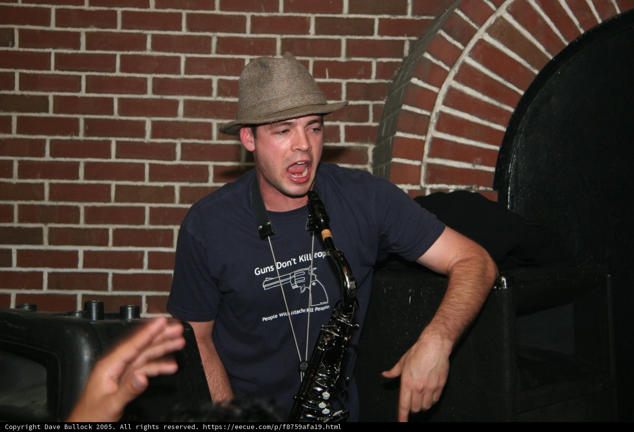 Man in Fedora poses against brick wall