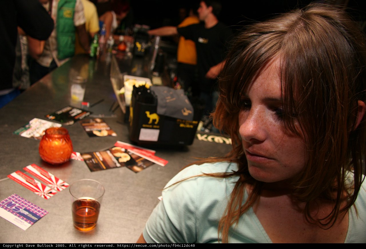 Pensive Young Woman at a Crowded Bar Counter