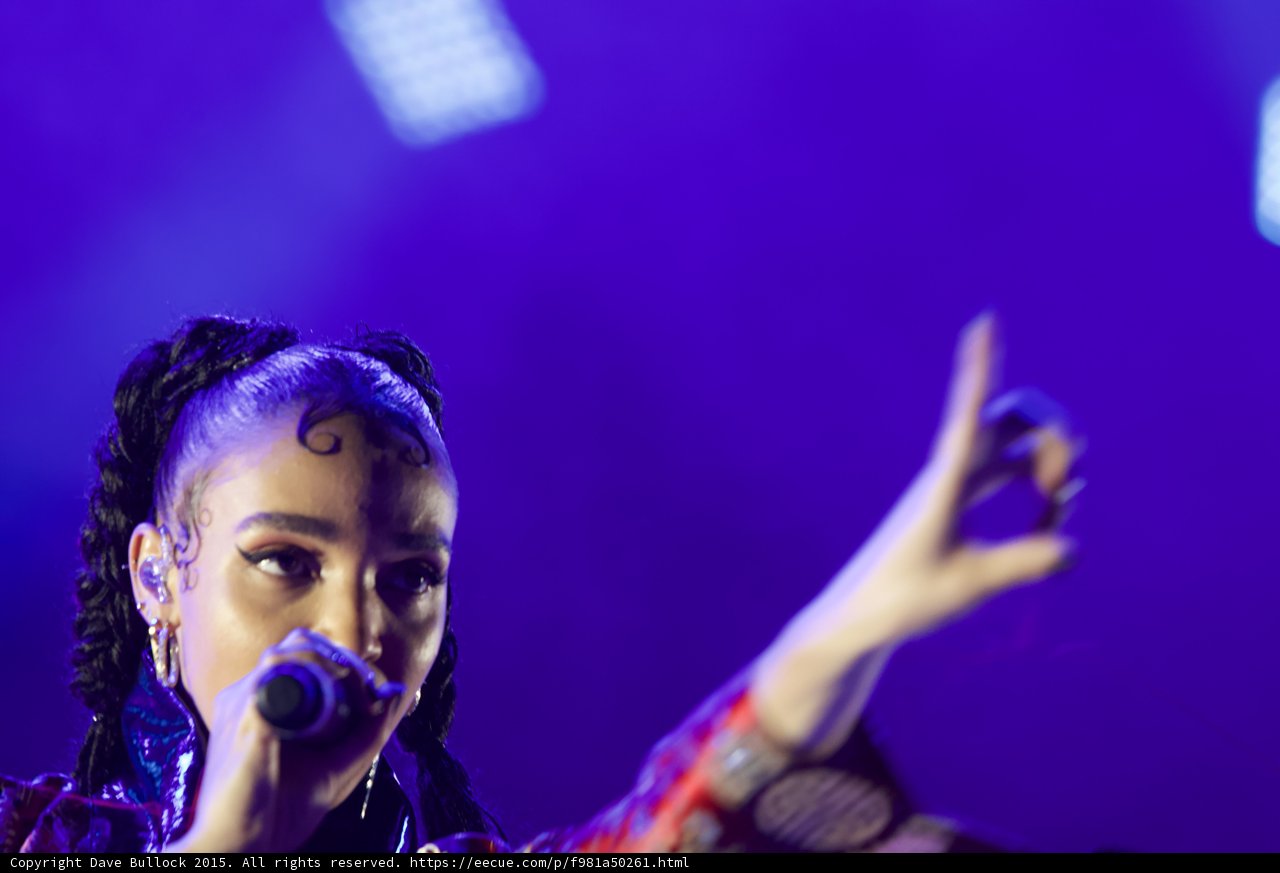 FKA twigs Close-Up Portrait Arm Extended Expressive Hand Gesture Ring Baby Hairs Swirls Cat-Eye Makeup Hoop Earrings Braided Ponytails Purple Blue Lighting LED Panel