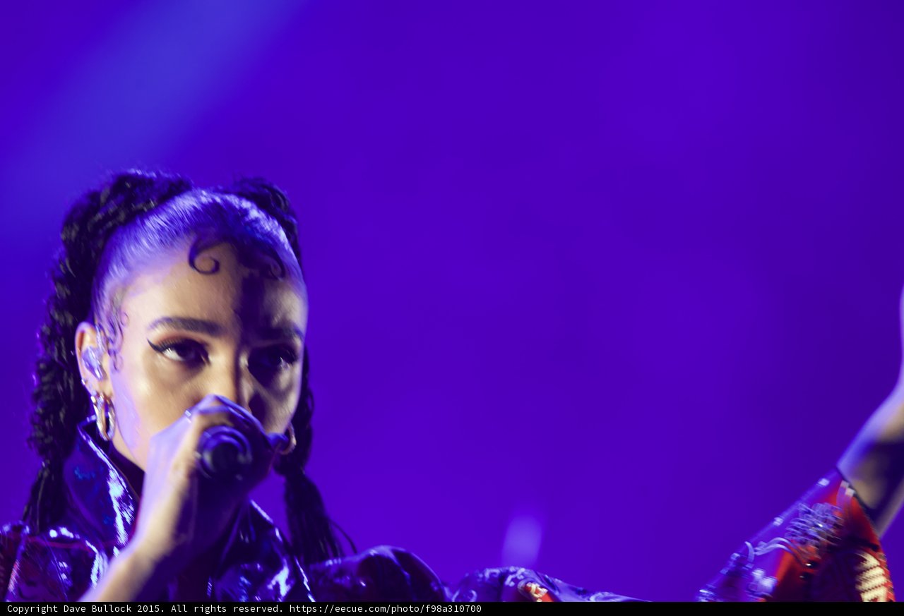 FKA twigs Dynamic Close-Up Portrait Arm Extended Motion Blur Kimono Sleeve Baby Hairs Swirls Cat-Eye Makeup Hoop Earrings Braided Ponytails Purple Blue Lighting
