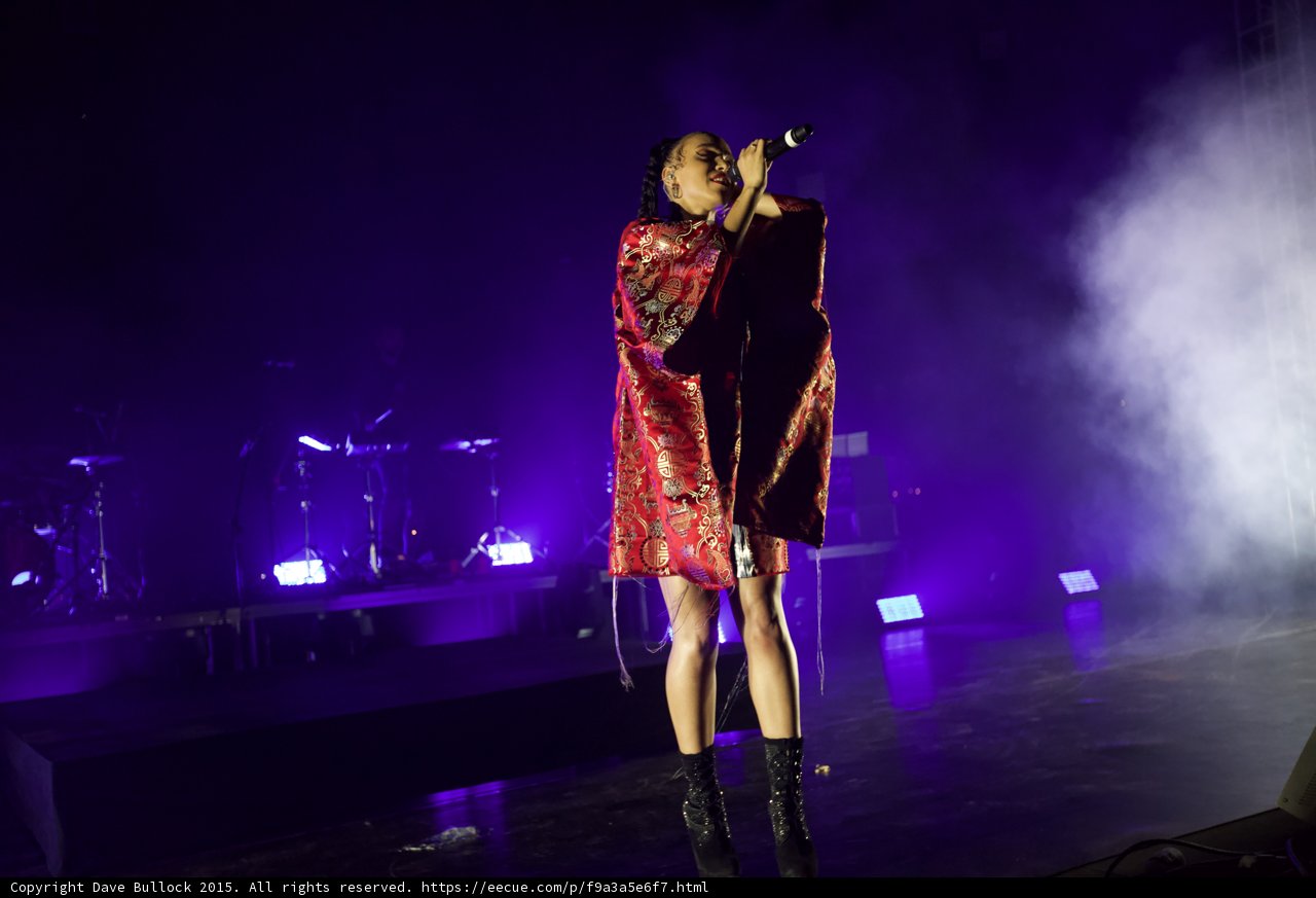 FKA twigs Full Body Singing Microphone Raised Looking Up Kimono Red Brocade Gold Patterns Black Bodysuit Boots Purple Lighting White Haze LED Panels Band