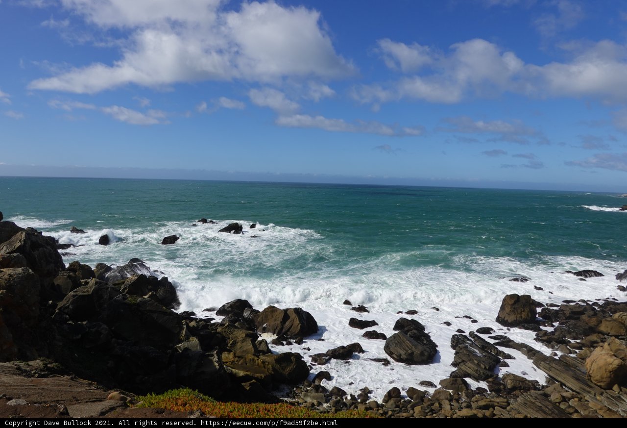 A Breathtaking View of the Ocean and Sky from a Rocky Cliff