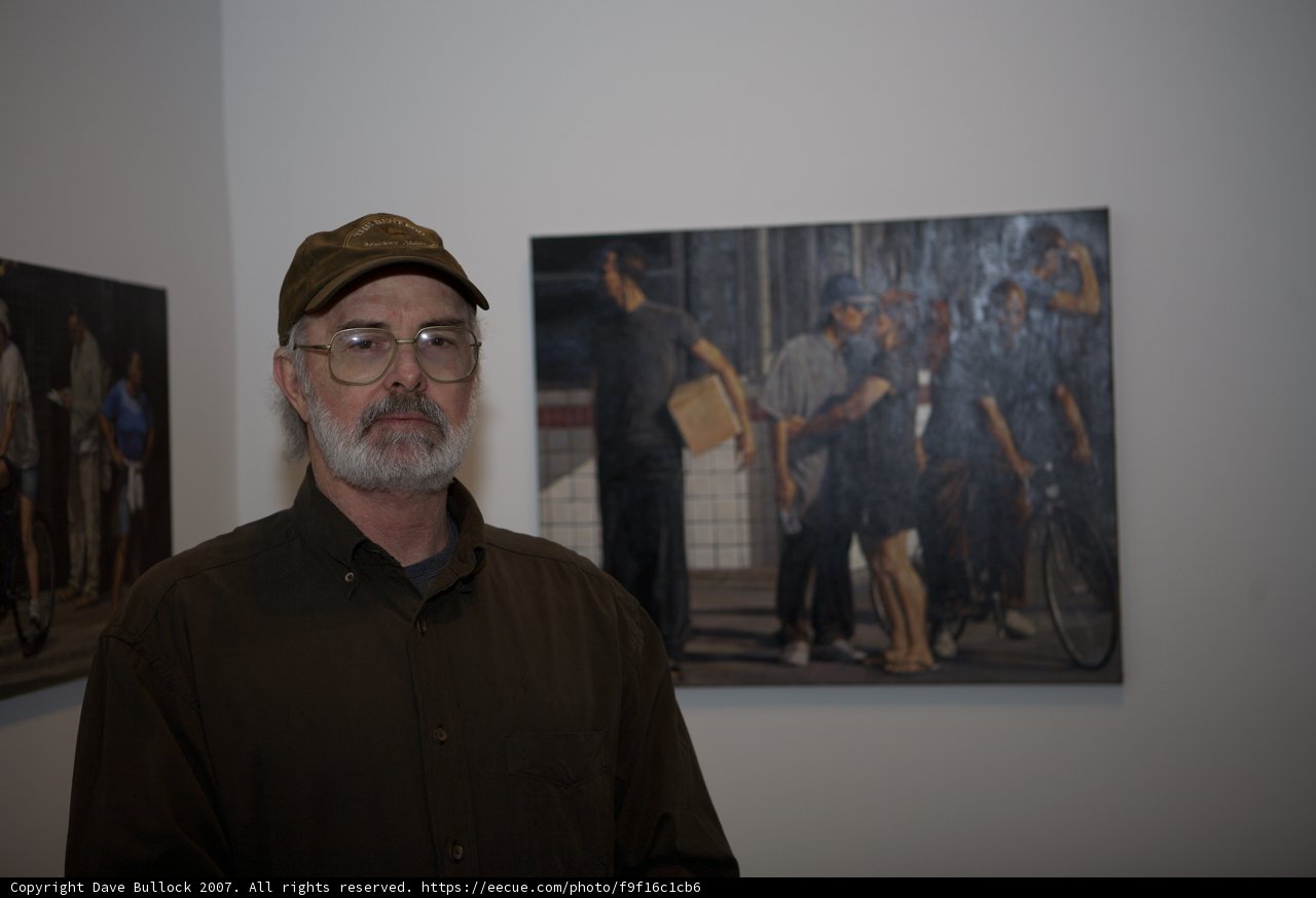 Man in Hat Admires Vibrant Paintings at Art Gallery