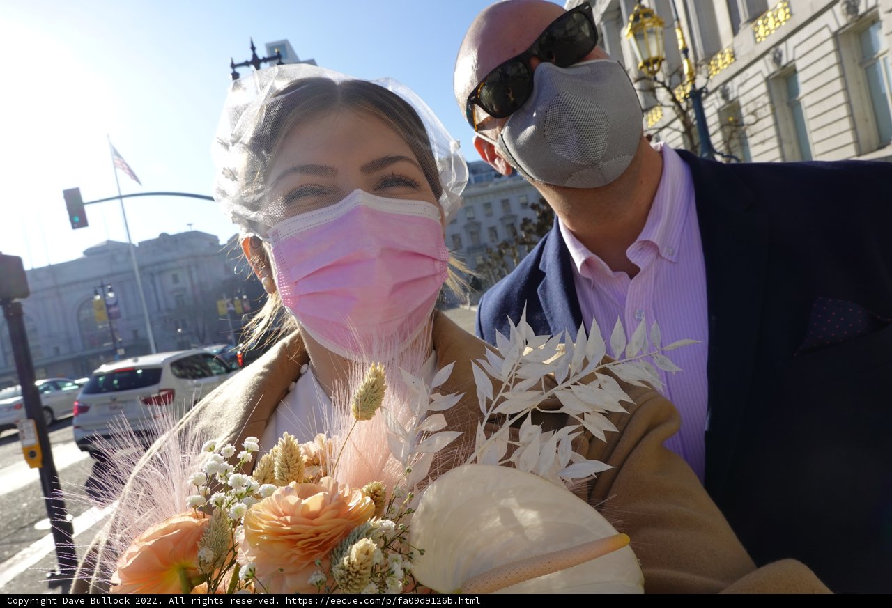 Masked Couple Walks Amidst Flower Beds on the Street