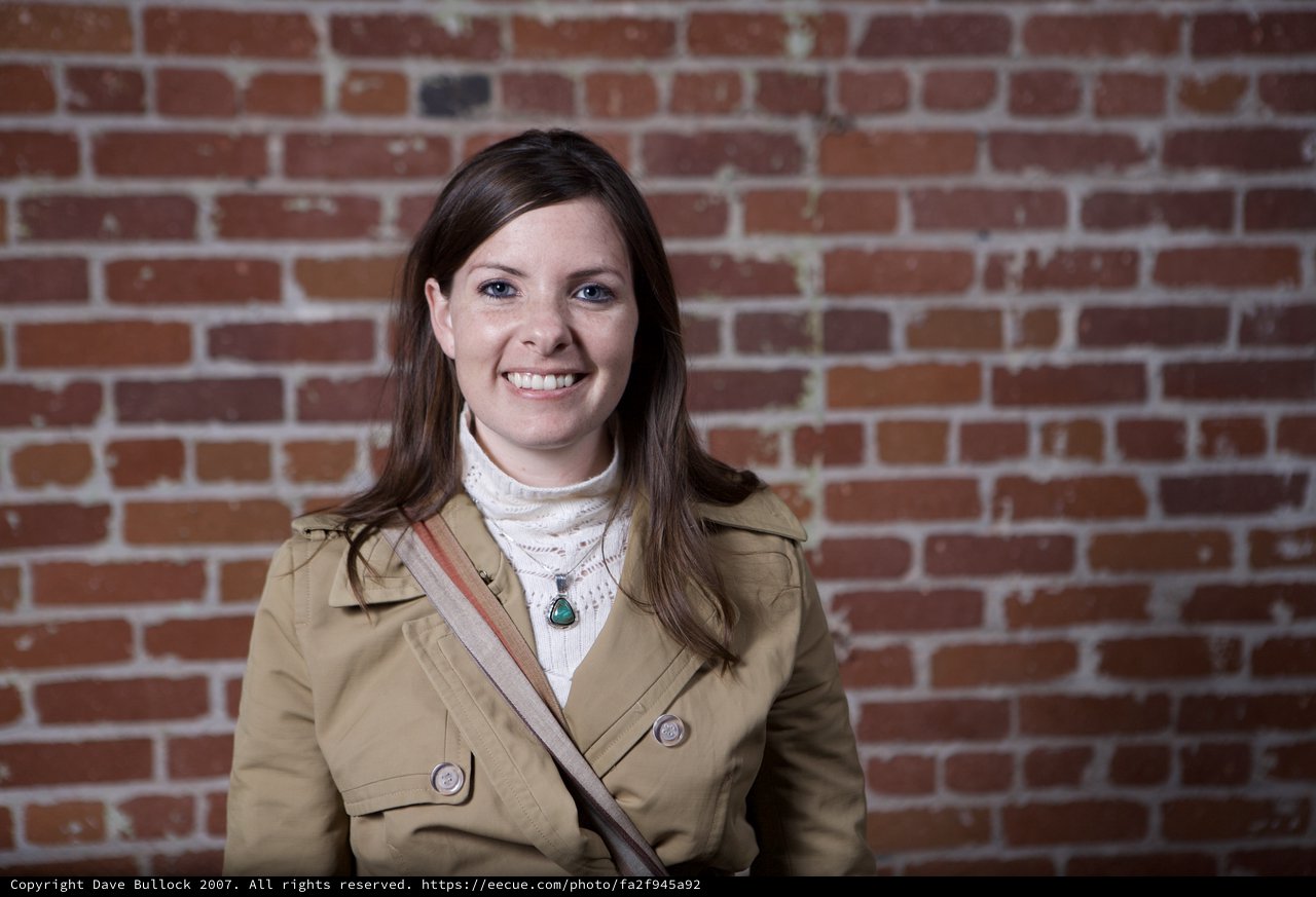Smiling Woman Poses Against Rustic Brick Wall