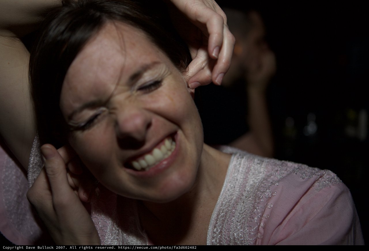 Woman Grimacing in Pain at Loud Nightclub