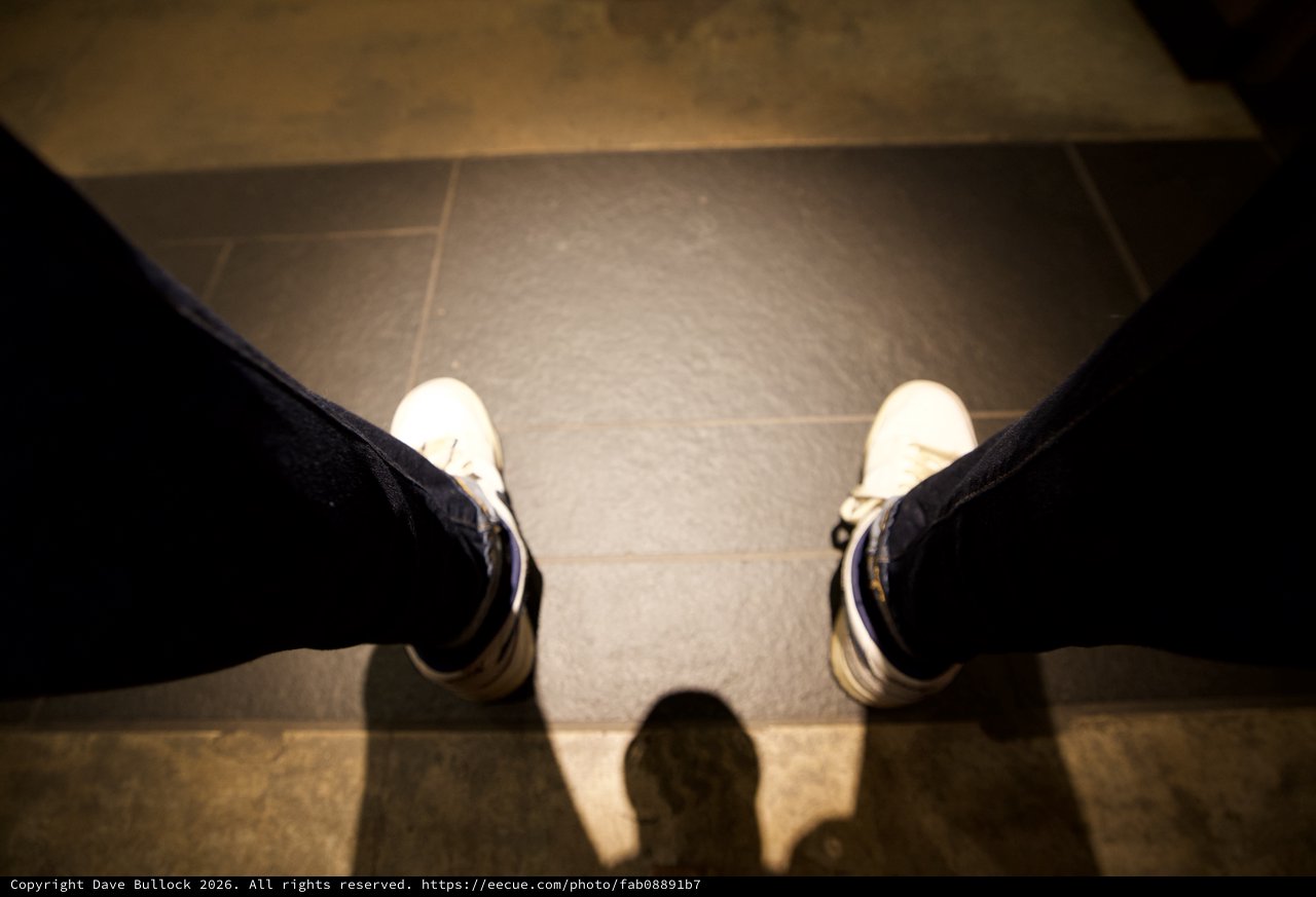 First-Person View: White Sneakers on Tiled Floor
