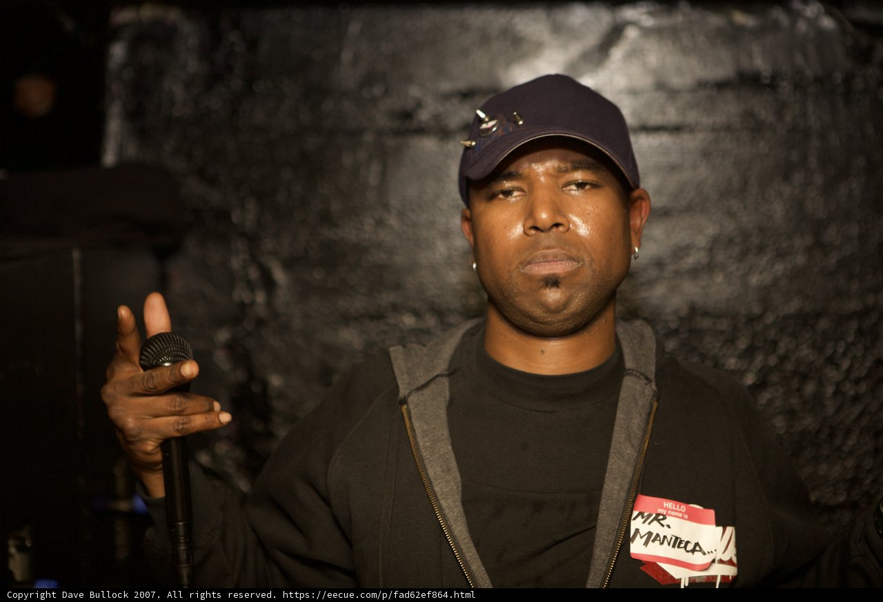 Steve J holding a microphone in a black hat and jacket