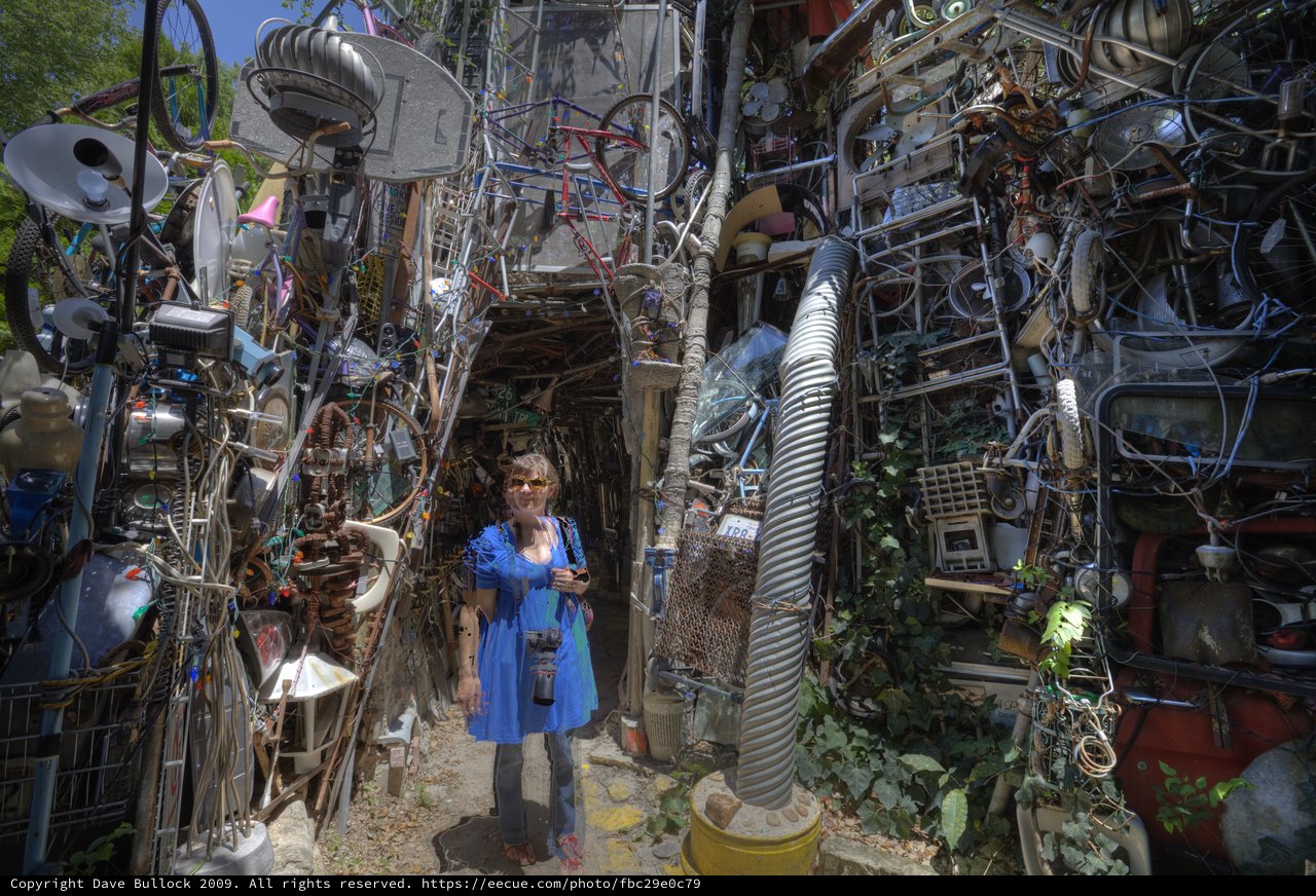 Woman Amid Towering Walls of Recycled Junk Art
