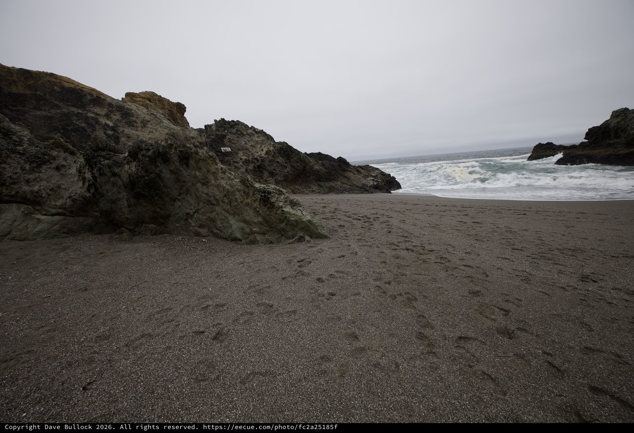 Dark Sand Beach Meets Dramatic Coastal Rock Formation