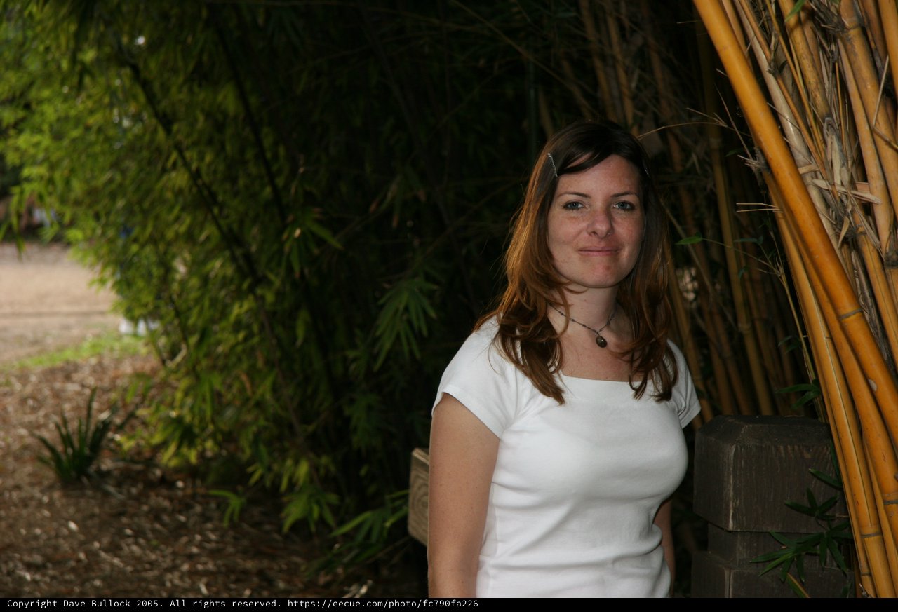 Woman Smiling Beside Bamboo Grove Pathway